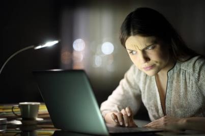 mujer sospechosa revisando contenido de computadora portátil en la noche - estafa de estudios fotografías e imágenes de stock