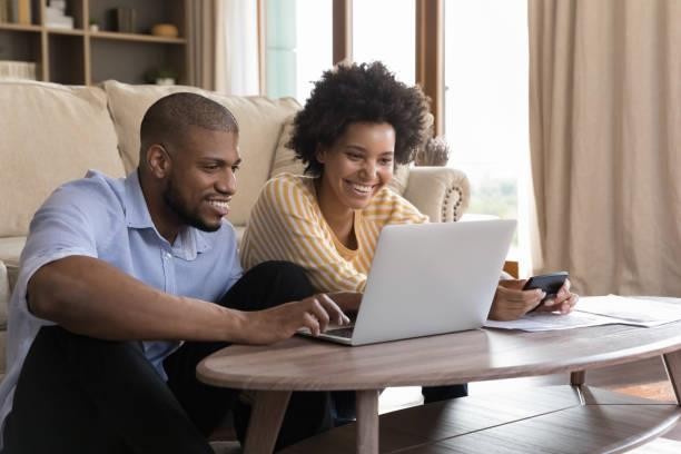 feliz joven pareja negra usando computadora portátil, mirando la pantalla, sonriendo - pago de impuestos fotografías e imágenes de stock